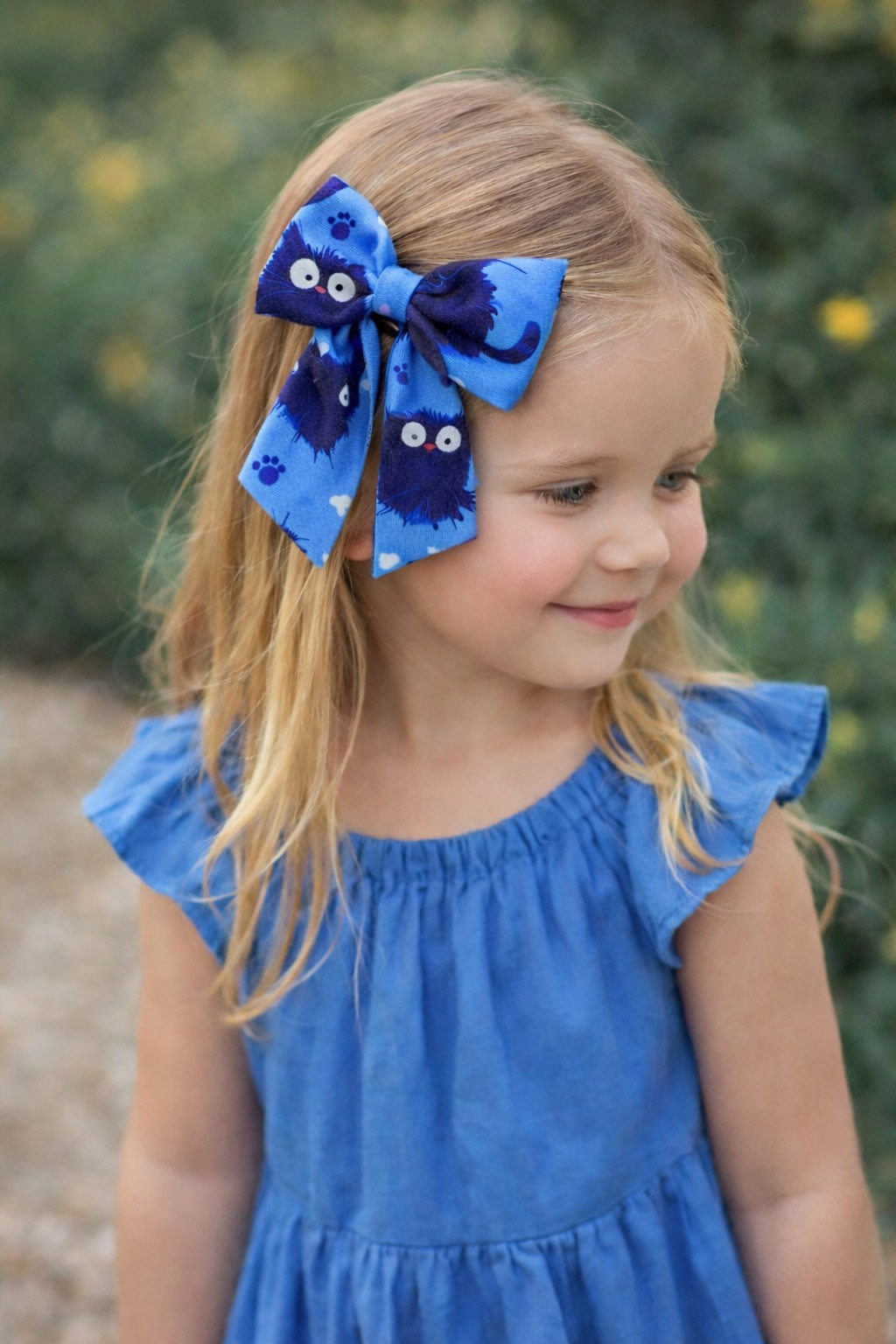 girl blue cats bow Little girl wearing a blue dress with a handmade blue cat print hair bow with short tails.