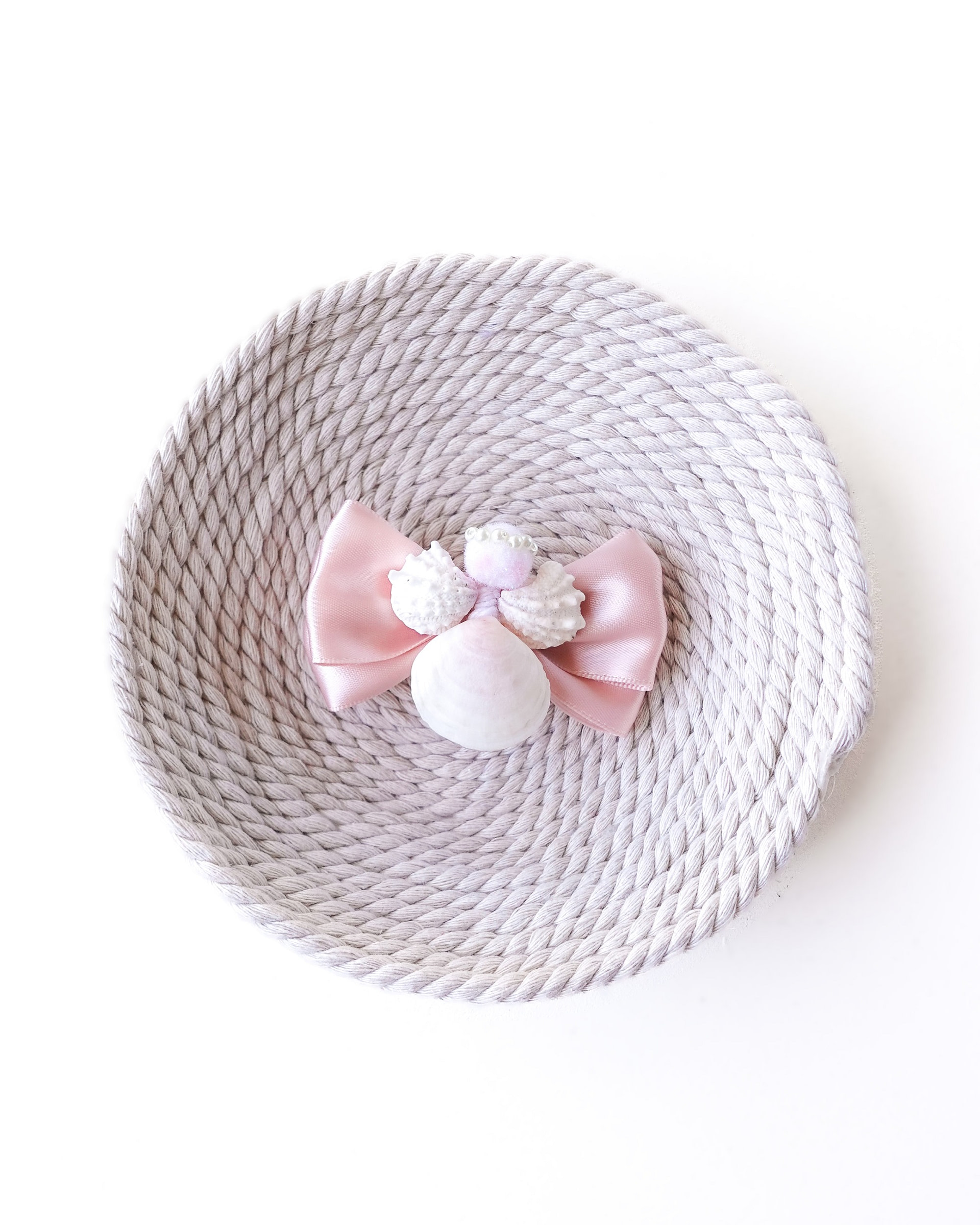 meow bowtique light pink bow with angel Handmade pink satin hair bow with seashell angel decoration on neutral woven background