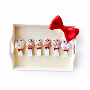 Handmade seashell hair clips set with red bows on a wooden tray