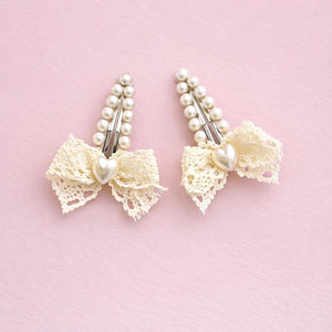 Pearl hair clips with ivory lace bows and heart-shaped pearl detail on a soft pink background