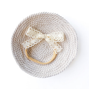 Handmade lace hair bow headband in ivory color on a soft neutral background